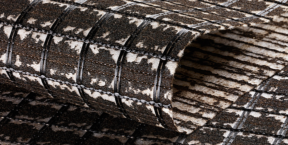 Armatura per asfalto SamiGrid® - primo piano del materiale Il composito SamiGrid® di griglia in PVA e tessuto non tessuto saturo di bitume in primo piano